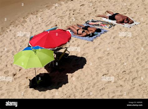 Des femmes se font bronzer seins nus sur une plage, les